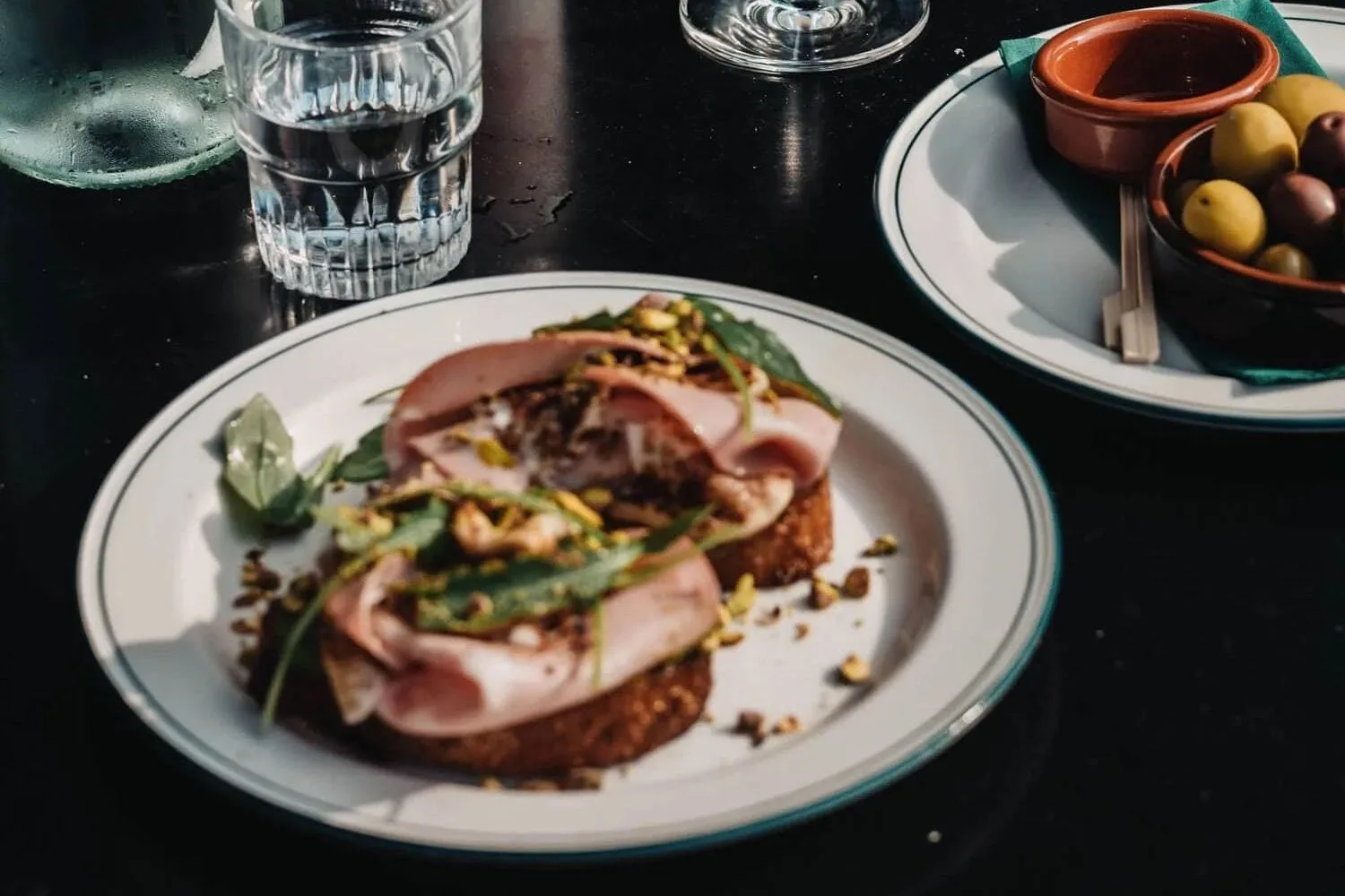 Wijn en tapas op tafel bij De Nada, met een glas met de naam erop