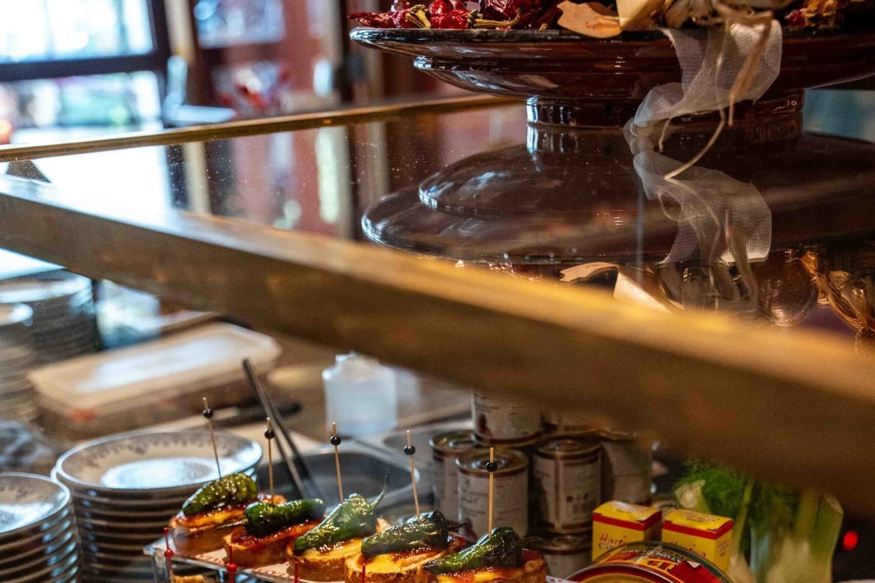 Toonbank met pintxos op stokbrood, ansjovis, olijven, gele paprika en conservenblikken