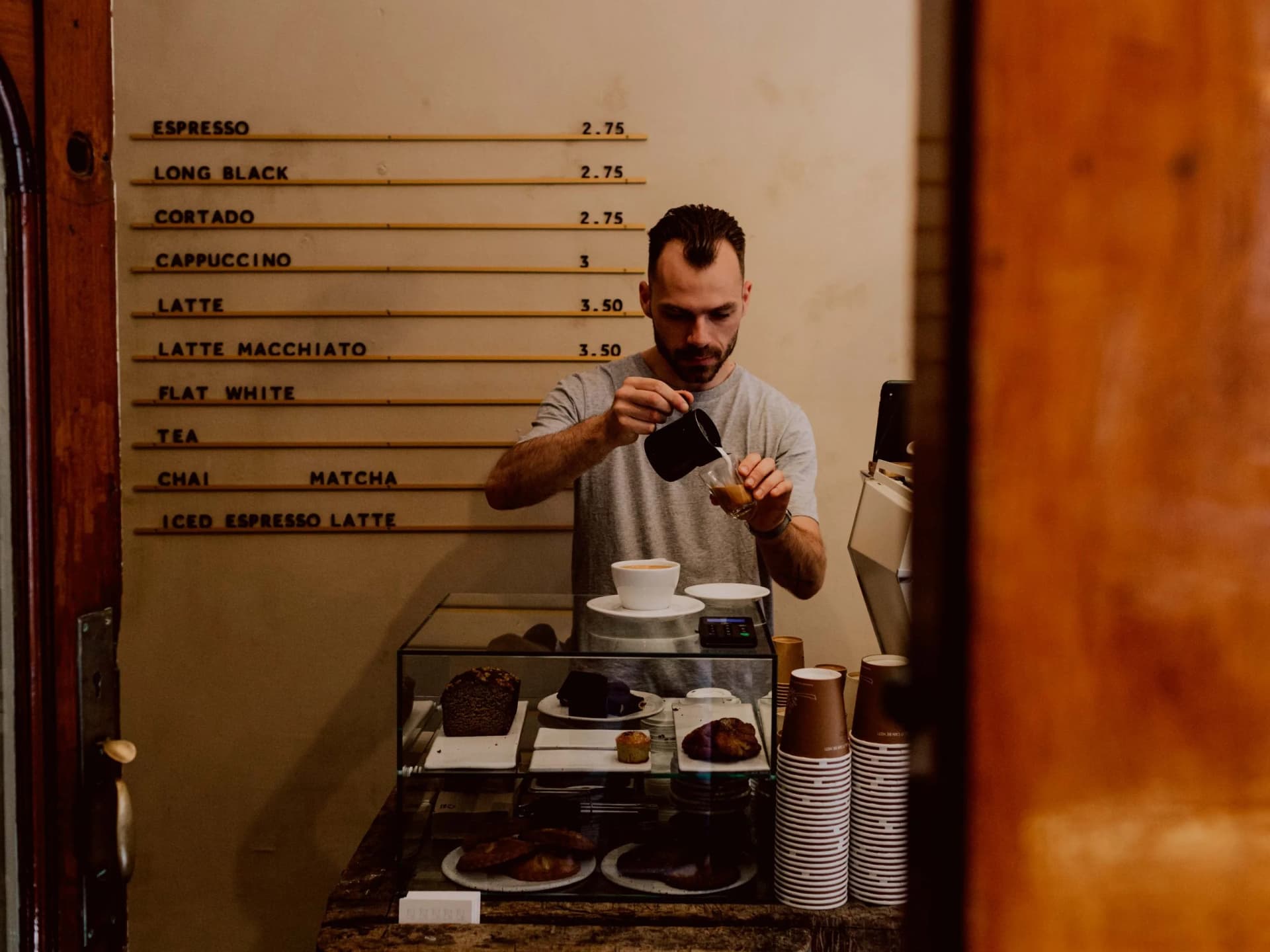 Barista schenkt melk in een koffie bij Ax Specialty Coffee