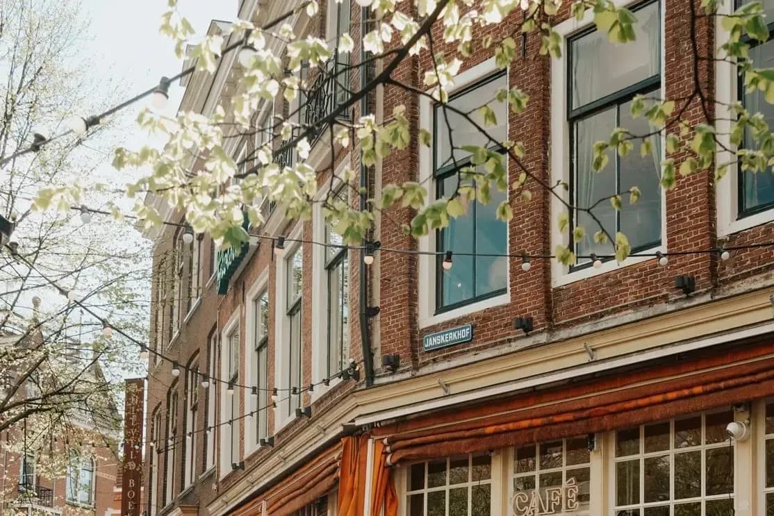Terras met stoelen en tafels langs de gevel van Café Carel aan een klinkerstraat