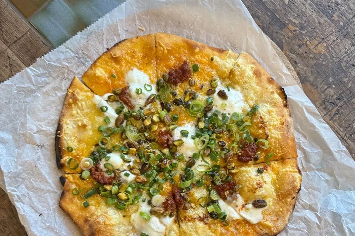 Houtoven-pizza met pistachenoten en lente-ui