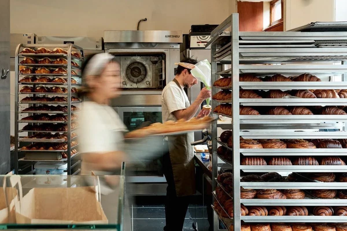 Bakkers aan het werk tussen rekken vol croissants