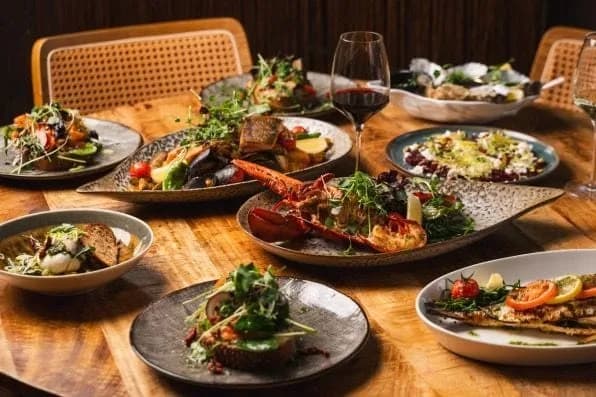Gedekte tafel vol gerechten bij Het Zuiden, met kreeft en vis