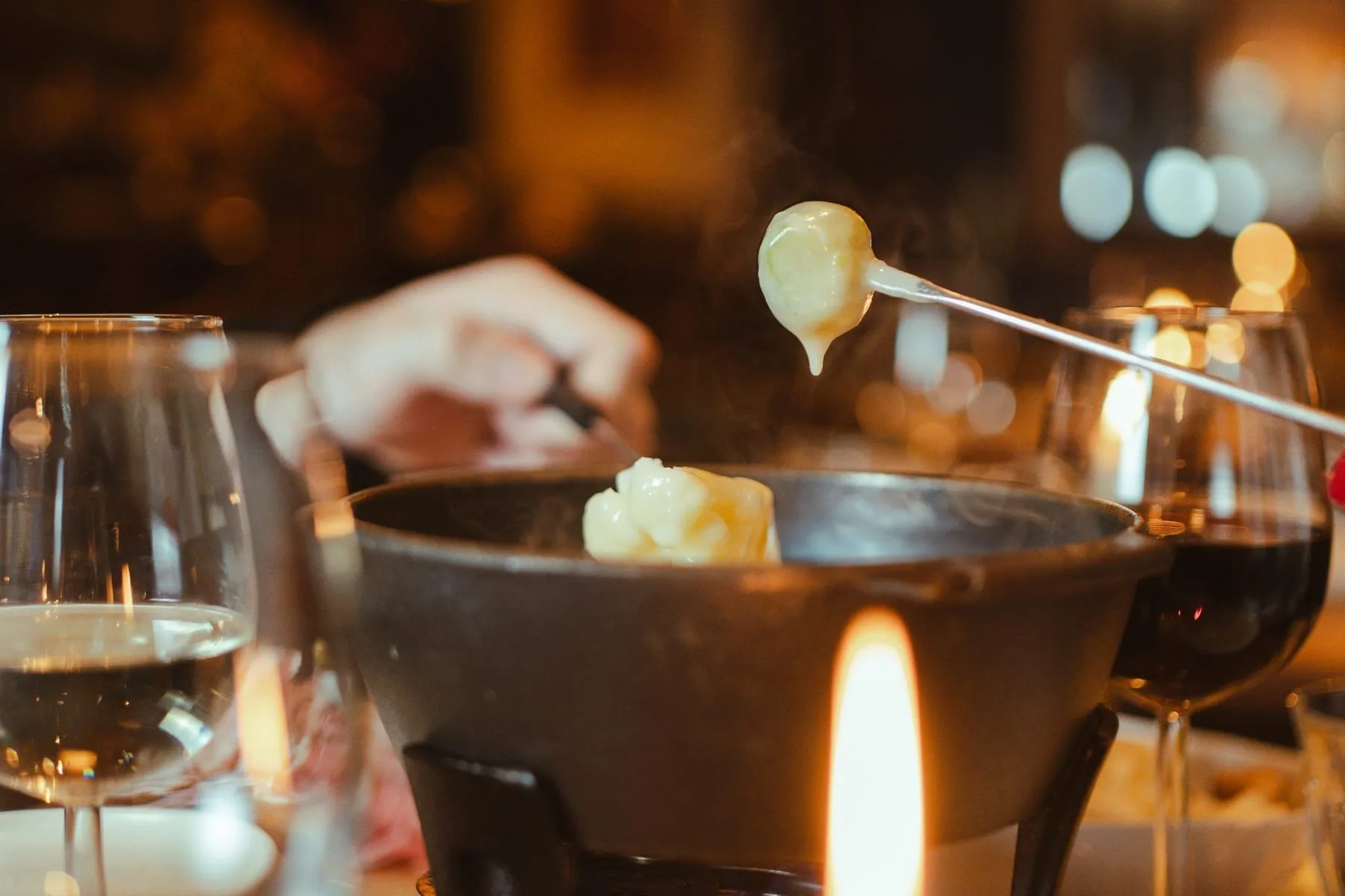 Kaasfondue met gesmolten kaas op een vork boven de pot